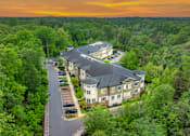 Thumbnail 1 of 54 - A large building surrounded by trees with a sunset in the background.