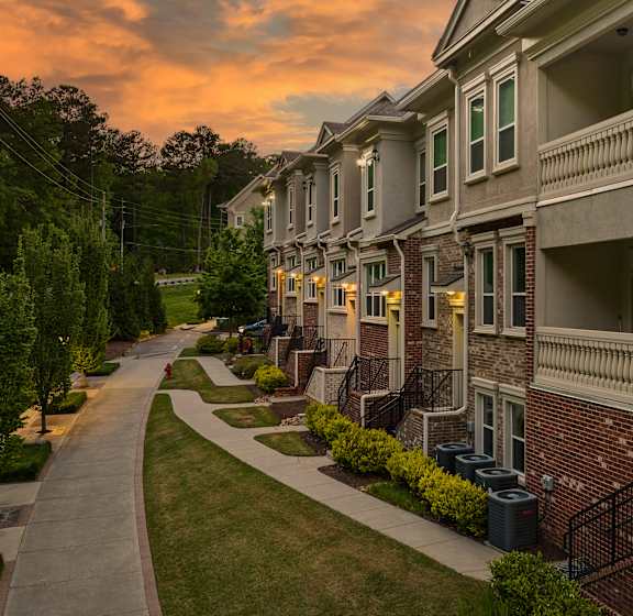 A row of townhouses with a sidewalk in front.