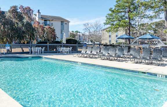 A large swimming pool with chairs around it.