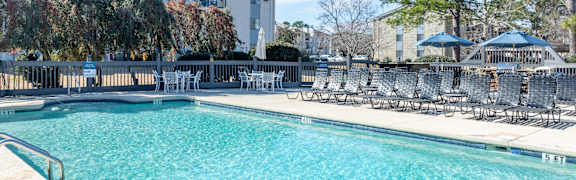 A large swimming pool with chairs around it.