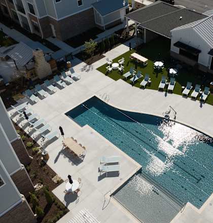 An aerial view of a swimming pool surrounded by lounge chairs and buildings.