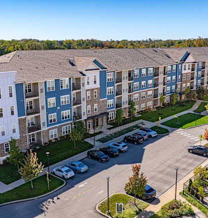 A large apartment complex with a parking lot in front.