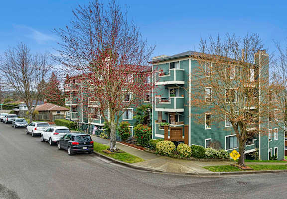a green apartment building with cars parked in front of it