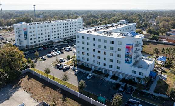 A large white hotel with a parking lot in front.