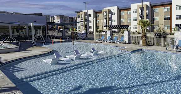 a resort style pool with white swans in it with an apartment building behind it