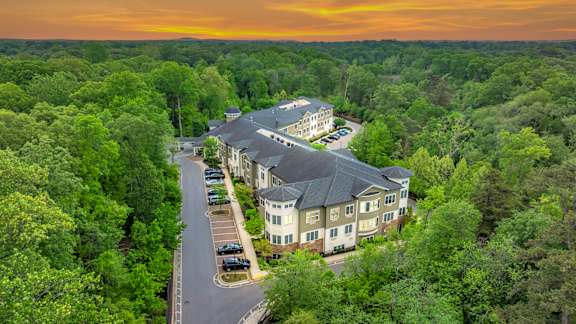 A large building surrounded by trees with a sunset in the background.