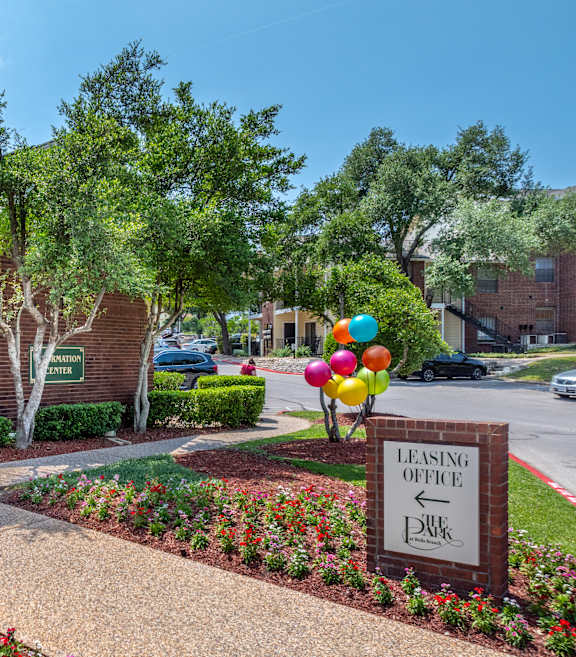 A leasing office is located in a landscaped area with a striped awning.