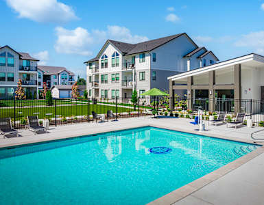 A swimming pool in front of a building with a black fence around it.