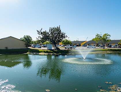 A fountain in the middle of a pond in a sunny day.