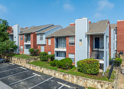 A parking lot in front of a red brick apartment building. at Wildwood Apartments , Austin, 78752