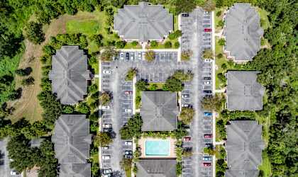 A bird's eye view of a residential area with houses, cars, and a pool.