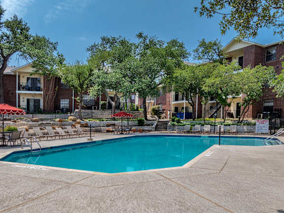 A patio with a couch, chairs, and a table with a tree in the background.