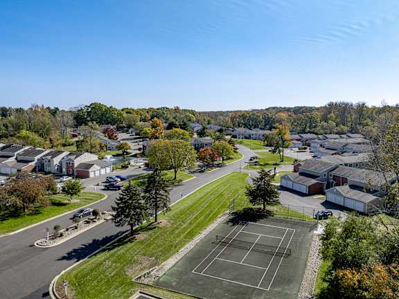 a neighborhood of houses with trees in the background and a parking lot in the foreground