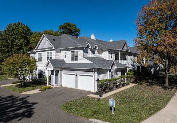 A large, well-maintained house with a grey roof and white walls.