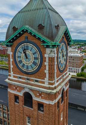A large clock tower with a green roof stands over a cityscape.