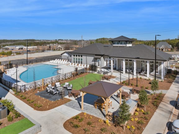 an aerial view of a resort style pool and clubhouse with tables and chairs