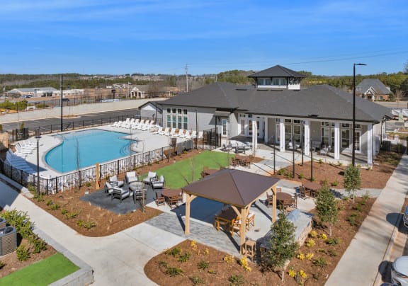 an aerial view of a resort style pool and clubhouse with tables and chairs
