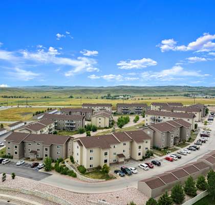 A large apartment complex with a parking lot in front.