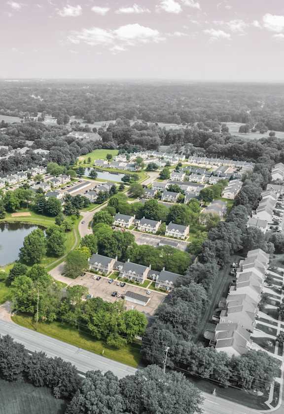 A bird's eye view of a residential area with houses, a lake, and a road.