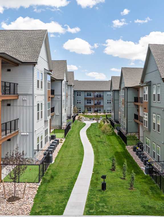 A row of modern townhouses with a green lawn in between.