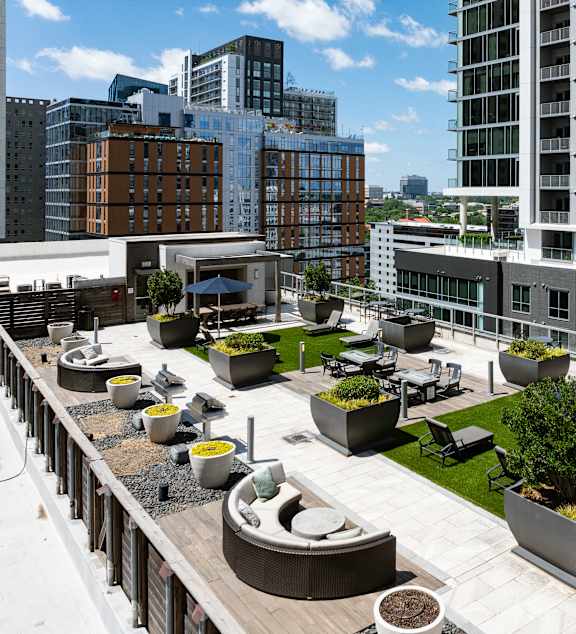 A rooftop patio with tables and chairs overlooks a city skyline.