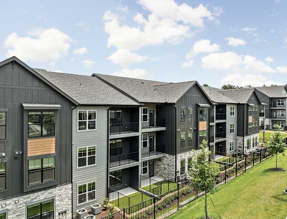 A row of modern townhouses with balconies and black fences.