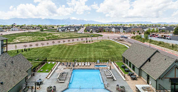 A large swimming pool surrounded by a grassy area and a building in the background.