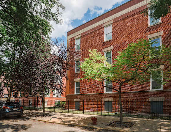 A red brick building with a tree in front of it.