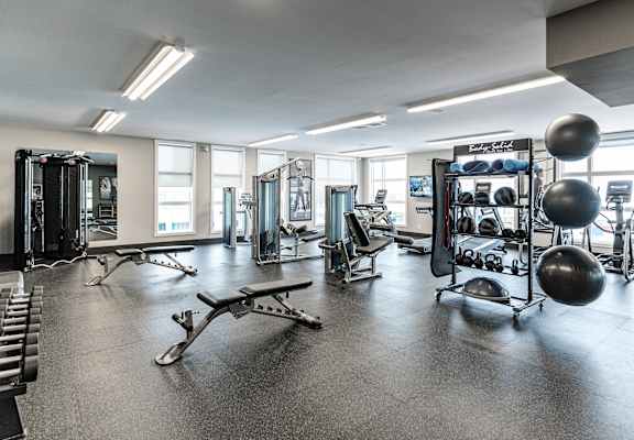 A gym with a variety of equipment including weights and exercise balls.