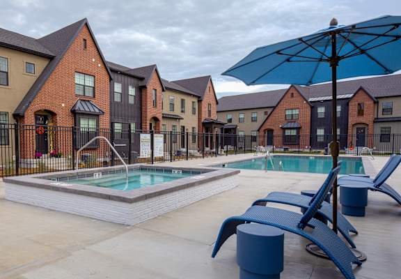 our apartments at the district feature a pool and patio with chairs and an umbrella