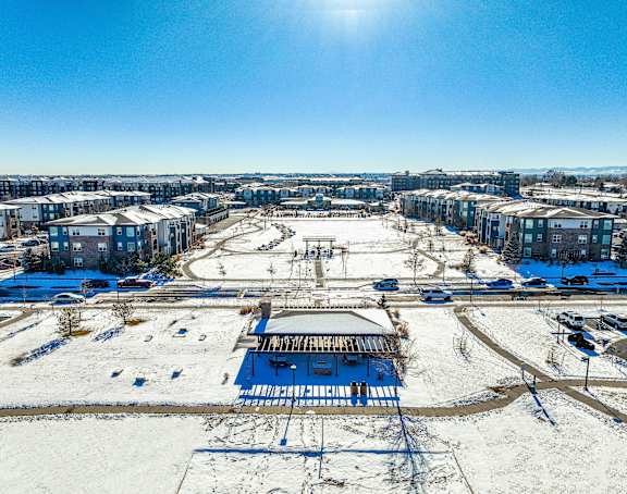 A sunny day in a snowy residential area with a blue building in the foreground.