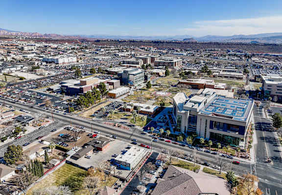 A cityscape with a large building in the center and a mountain range in the background.