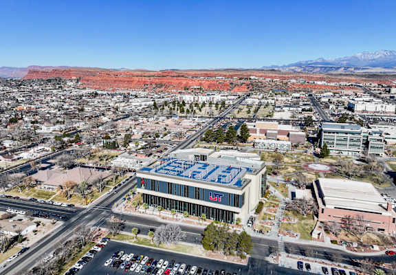 A cityscape with a prominent building in the center and a mountain range in the background.
