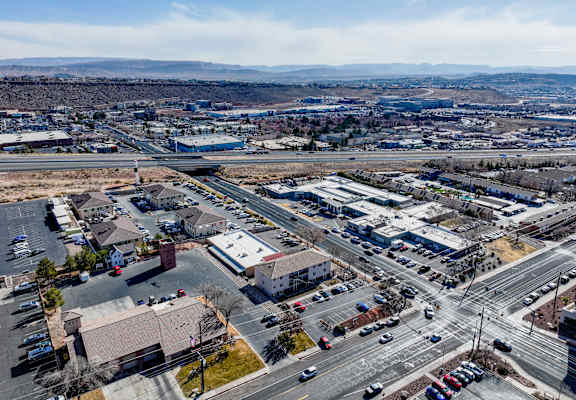 A large parking lot with several cars and buildings in the background.