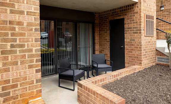 a patio with two chairs and a table outside of a building