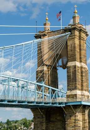 A bridge with a blue suspension bridge and a brown tower with a flag on top.