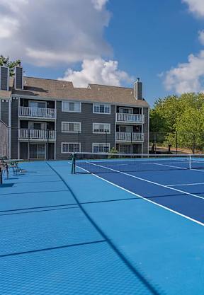 A tennis court in front of a grey building.