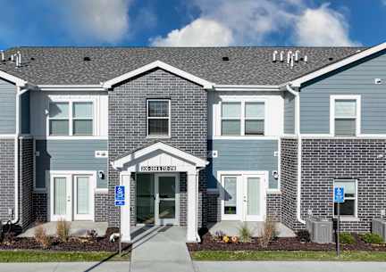 A blue and white townhouse with a front yard and a driveway.at Hawthorne Pointe, Bondurant, IA