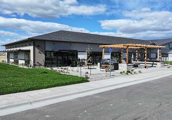 A modern building with a grey roof and a white fence in front at Yellowstone Landing, Belgrade, MT, 59714.