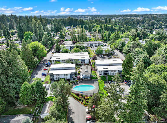 A large building complex surrounded by trees and a pool in the middle.