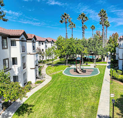 A sunny day at a residential complex with a green lawn and palm trees.