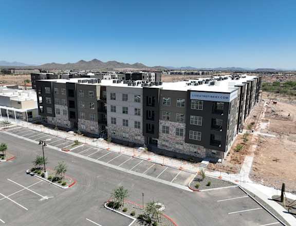 A large building under construction with a parking lot in front.