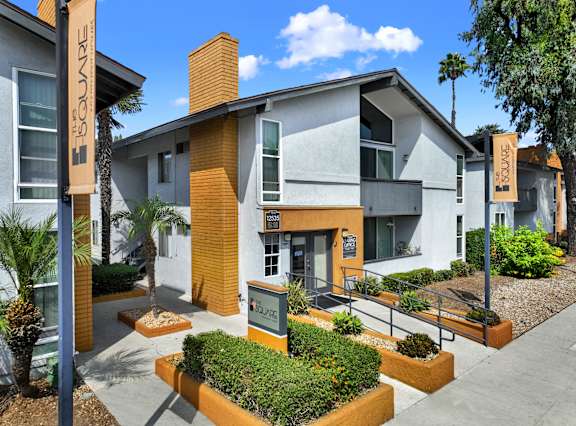 A building with a yellow and grey exterior and a sign that reads at The Square in Downey, CA, 90242