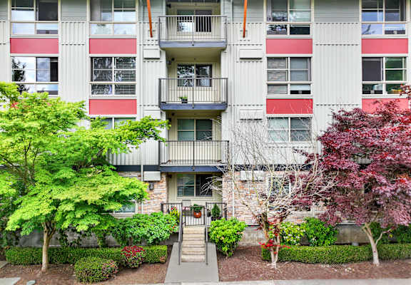 A building with a balcony and a small garden in front.