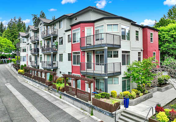 A row of multi-story apartment buildings with balconies and flower pots on the steps.