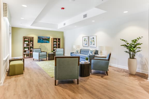 a resident clubhouse with couches chairs and a bookshelf