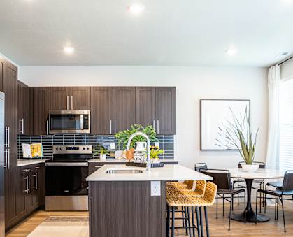 A modern kitchen with a refrigerator, sink, and dining table.