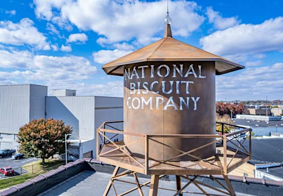 A large sign for the National Biscuit Company stands in front of a building.