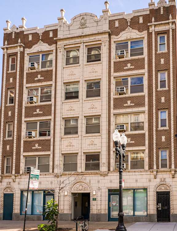 A tall building with a brown facade stands in front of a red brick building.