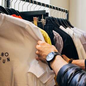 A person is holding a white t-shirt with the text "NO FUN" on it.